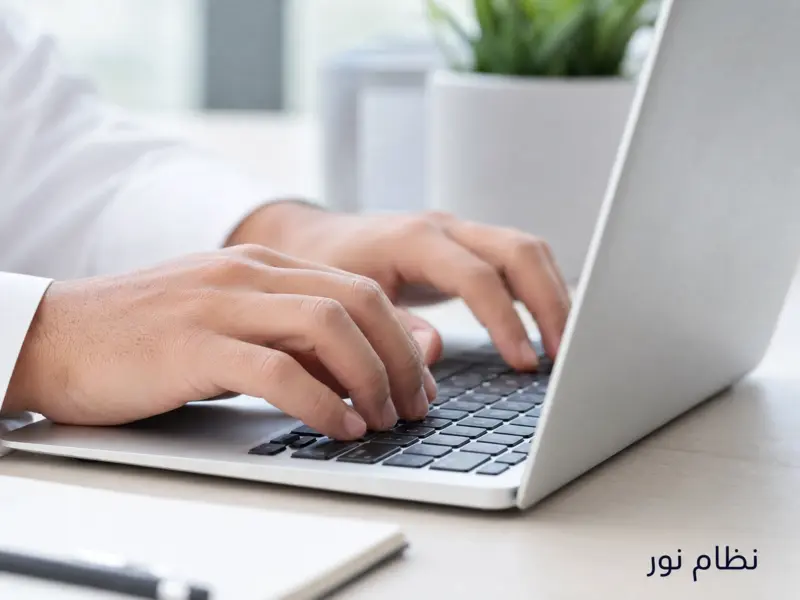 شخص يقوم بكتابة بيانات تسجيل الدخول إلى نظام نور على لوحة مفاتيح الحاسوب.